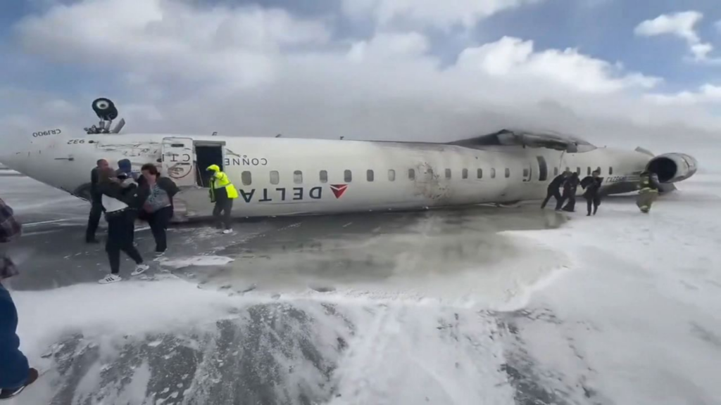 Delta Flight 4819 is seen upside down near the runway after crashing while landing in Toronto.