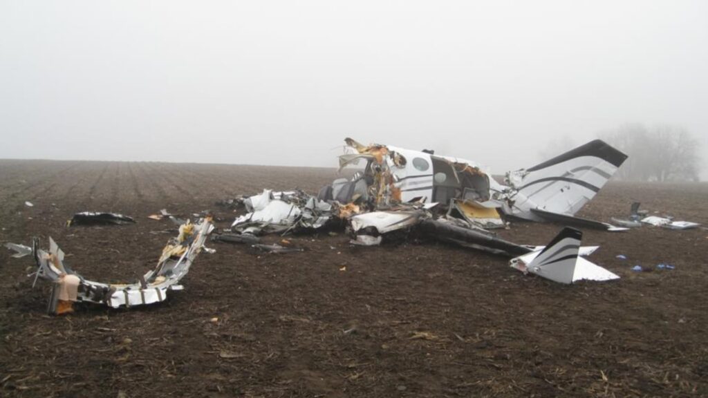 Wreckage of Cessna 414A N789UP scattered across a muddy cornfield under low visibility fog after a fatal crash near Bloomington, Illinois.