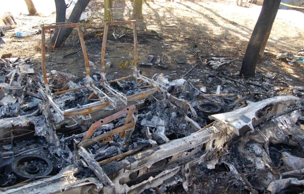 Charred remains of the cockpit showing burned seat frames and melted structure after a post-crash fire.