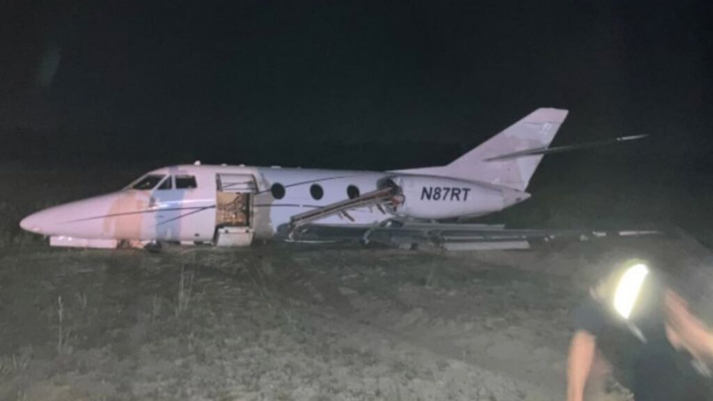 Dassault Falcon 10 N87RT resting off the end of the runway in Panama City, Florida after a runway excursion, with the main landing gear collapsed and the cabin door open.