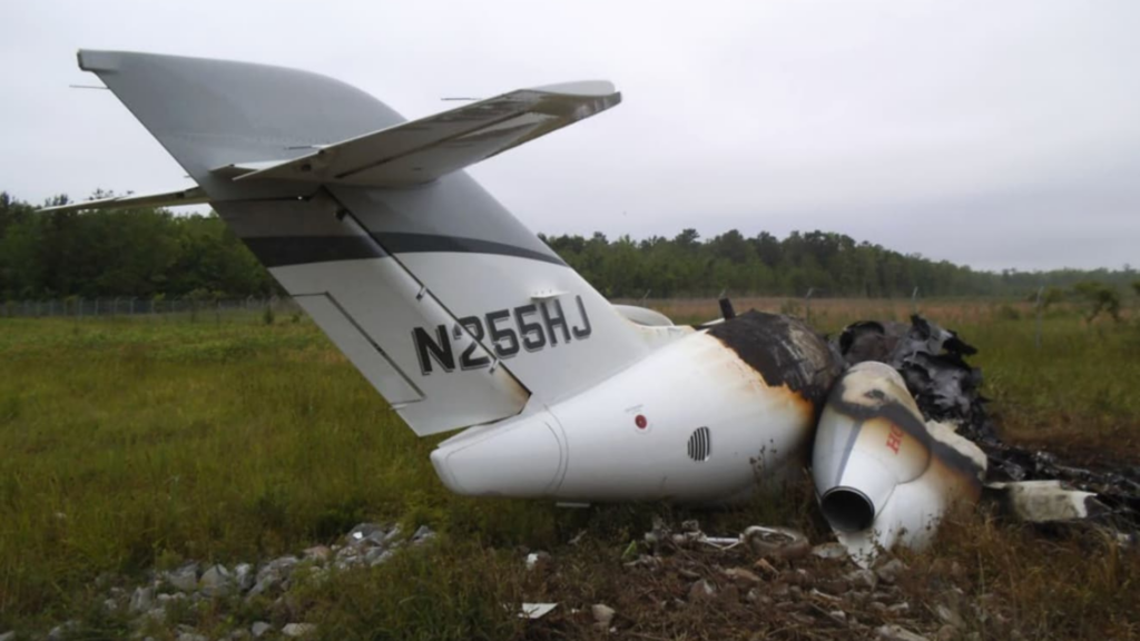 Close rear view of the aircraft’s tail section with registration N255HJ visible, extensive fire damage to the fuselage, and the right engine burned.