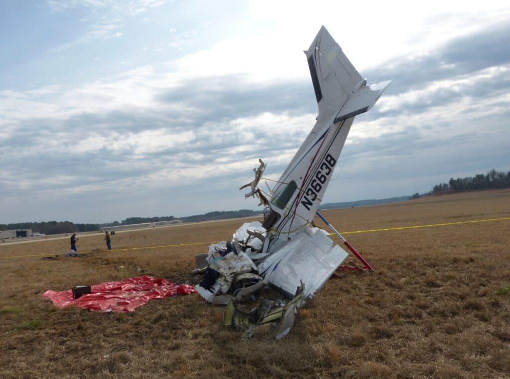 Accident scene showing Beechcraft 95-B55 Baron N36638 wreckage embedded nose-down in a grassy field beside the runway at LaGrange-Callaway Airport.