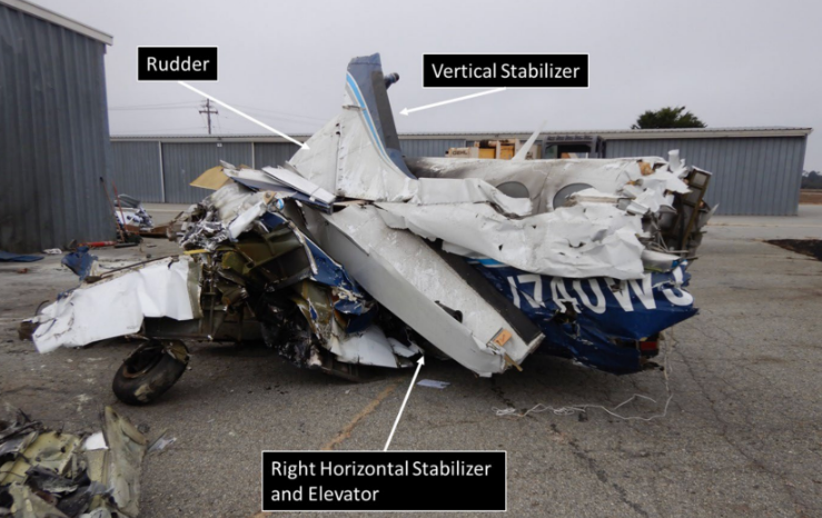Crushed blue-and-white aircraft wreckage on an airport ramp, with labels pointing to the rudder, vertical stabilizer, and right horizontal stabilizer and elevator.