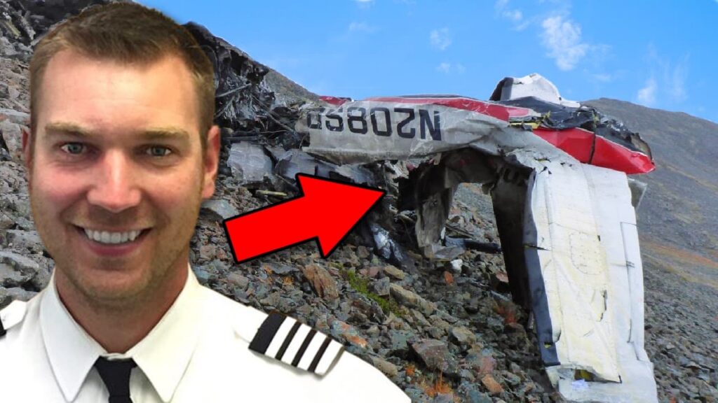 Pilot standing in the foreground beside the wreckage of a small airplane on a rocky mountainside, with a large red arrow pointing toward the damaged fuselage.