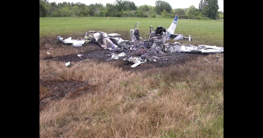 MIA08FA144 — Photo 6 - View of right wing impact with ground with separated propeller and main wreckage in the background. Photo NTSB.JPG, page 1 (NTSB docket)