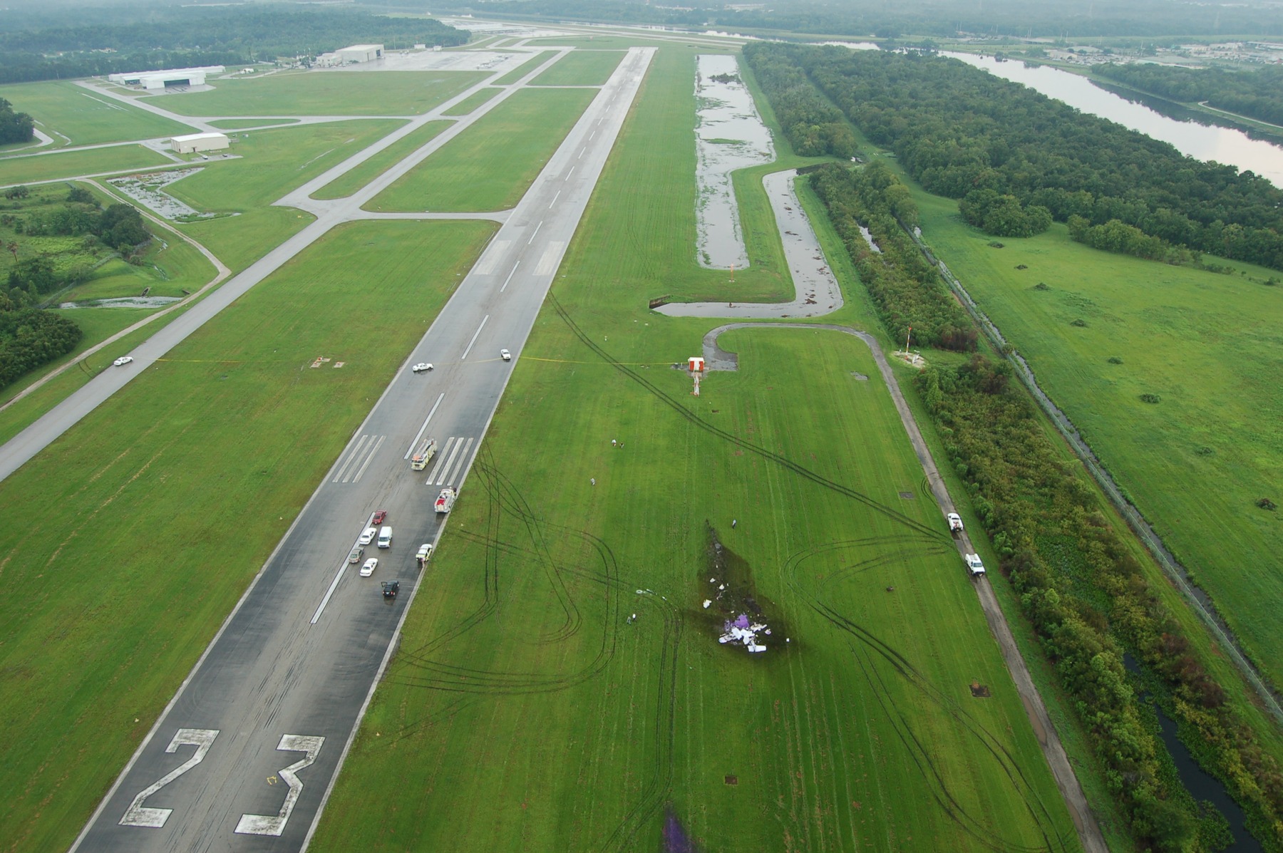 MIA08FA144 — Photo 1 - Aerial view of crash site looking down the crash debris line towards runway 5. Photo Hillsbourogh Sheriffs Dept, page 1 (NTSB docket)